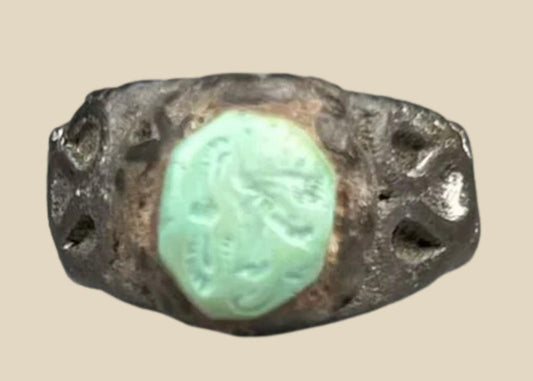 Ancient Neo-Assyrian silver ring from Mesopotamia (modern-day Iraq), 9th–7th century BCE, featuring a raised turquoise bezel and engraved winged serpent with mythical beast motifs. Silver band with natural patina showcases Assyrian craftsmanship, symbolizing divine protection, authority, and spiritual power.