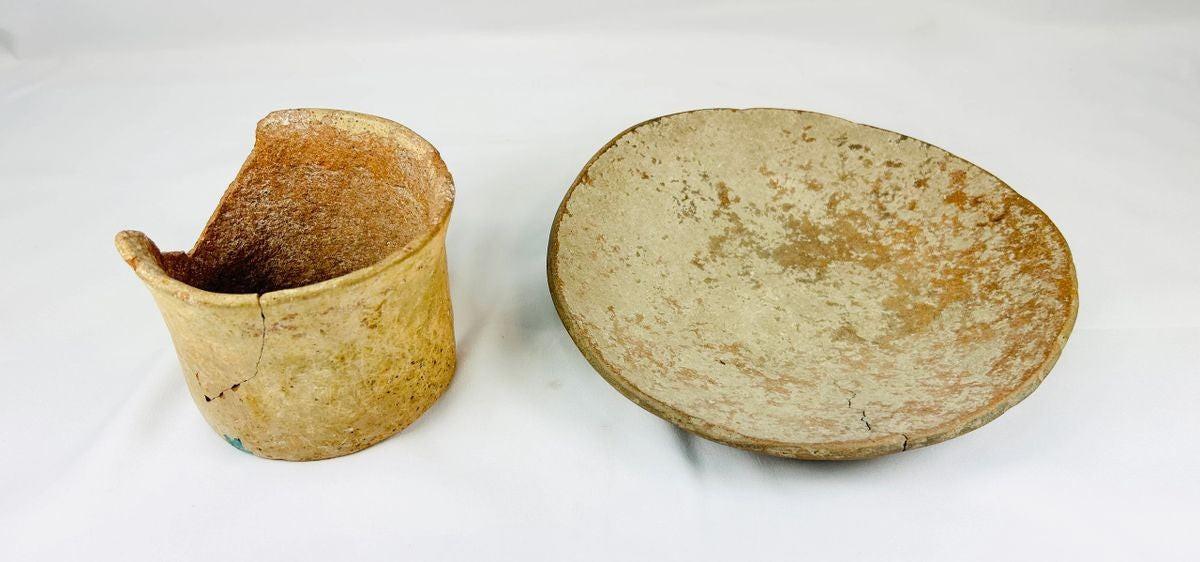 Set of Neolithic terracotta pottery, including a shallow bowl and cylindrical vessel fragment, circa 4000–2000 BCE, with natural earthy tones, unglazed surfaces, and aged patina.