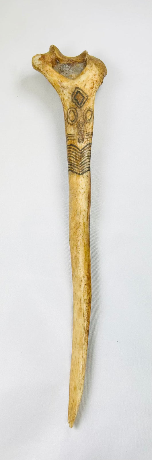 Antique New Guinea ritual bone dagger made from human humerus, shown vertically against a neutral background