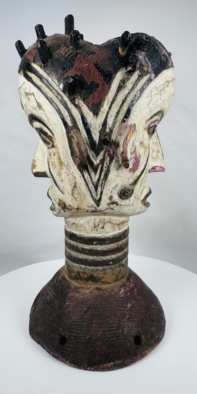 Traditional Igbo masquerade crest with opposing faces, projecting coiffure elements, and aged patina.