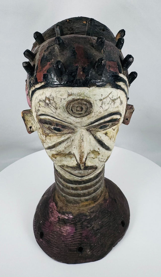 African ceremonial dance crest from the Igbo people with opposing faces and traditional masquerade construction.