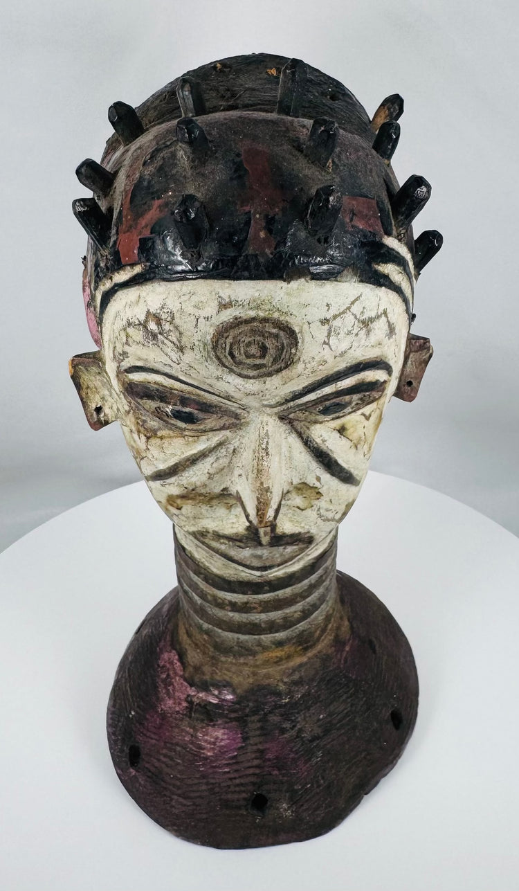 African ceremonial dance crest from the Igbo people with opposing faces and traditional masquerade construction.