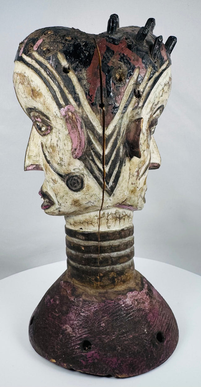 Mid-century Igbo masquerade headdress featuring a carved Janus head design and weathered surface patina.