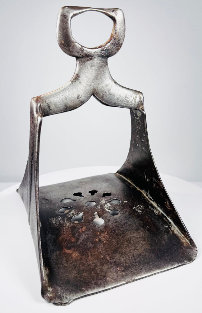 17th-century Ottoman forged steel stirrup with triangular form, pierced floral footplate, and traces of silver damascening.