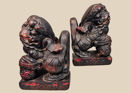 Antique Chinese Qing Dynasty wooden guardian lion pair with dark lacquer, red pigment and carved brocade balls