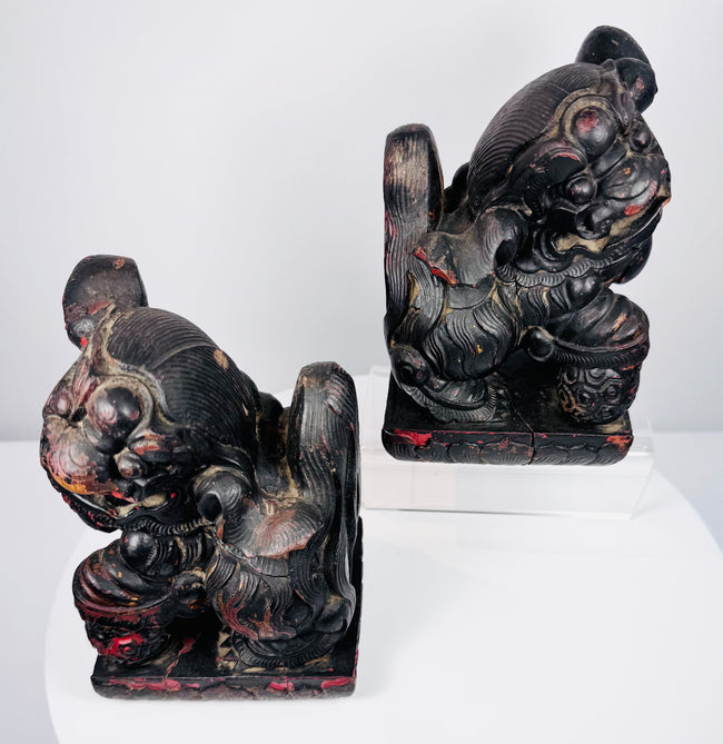 Three-quarter view of Qing Dynasty Chinese guardian lions showing carved collars, rounded pendants and aged lacquer surfaces