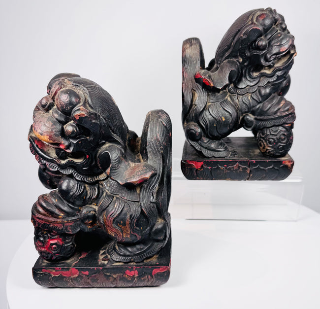 Antique Chinese Foo dog pair in mirrored poses with raised paws resting on patterned brocade balls