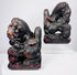 Antique Chinese Foo dog pair in mirrored poses with raised paws resting on patterned brocade balls