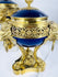 Close-up of a Louis XVI Revival vase displaying cobalt-blue porcelain, lion mask mounts, and ring handles.