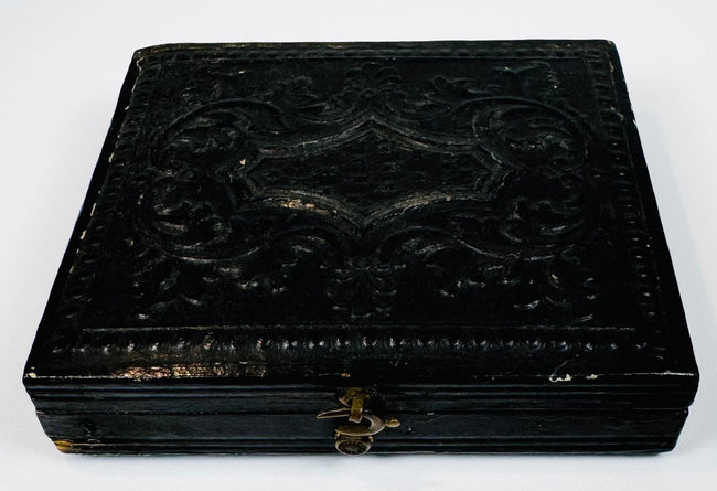 Closed mid-19th-century cased photograph with molded dark exterior, ornamental design, and metal clasp