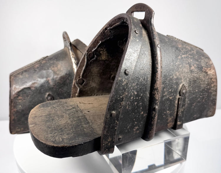 Close-up of hand-forged iron stirrup with suspension loop, rivets and aged leather lining