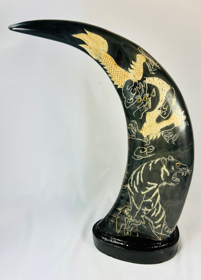 Mid–late 20th-century East Asian polished water buffalo horn sculptures etched and painted in gold with celestial dragons and prowling tigers amidst clouds, mounted on black lacquered bases, mirrored composition, circa 1960–1980.
