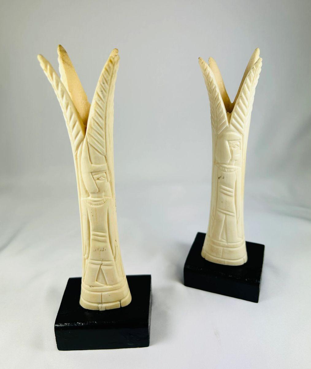 Pair of carved Egyptian ivory sistrum handles on black display bases, featuring stylized figures and decorative motifs, dating to the Third Intermediate Period, circa 1070–664 BCE.