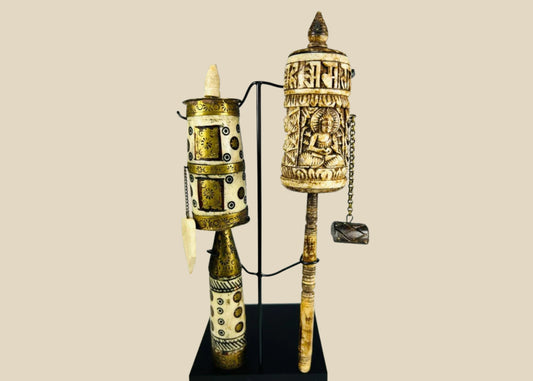 Pair of Tibetan prayer wheels, late 19th century, hand-carved bone, brass, and wood with Buddha figure, mantra script, floral motifs, and custom stands.
