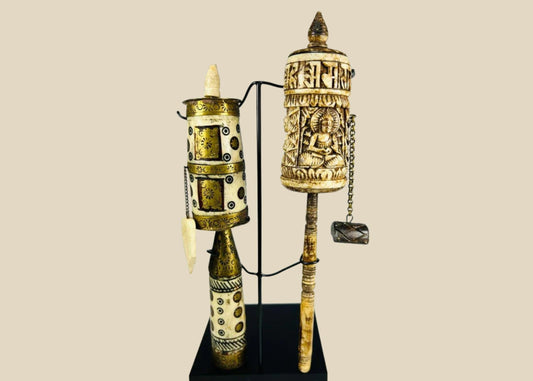 Pair of Tibetan prayer wheels, late 19th century, hand-carved bone, brass, and wood with Buddha figure, mantra script, floral motifs, and custom stands.
