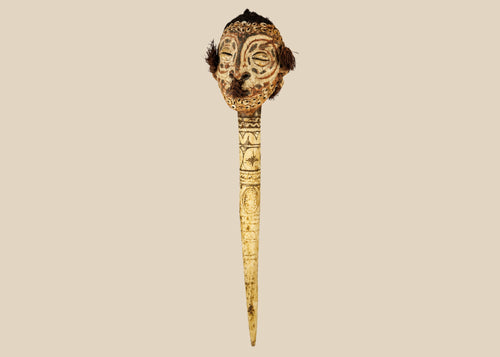 19th-century Sepik River ceremonial bone dagger with carved ancestral head, cowrie shell inlays, human hair adornments, and tribal geometric motifs, used in ritual and initiation rites.