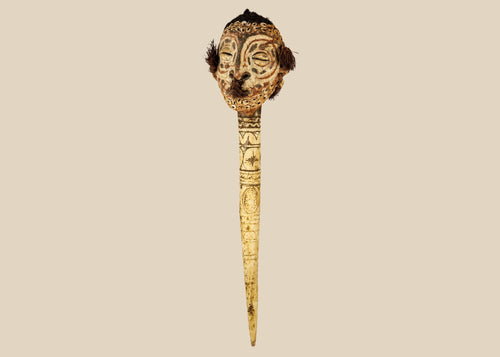 19th-century Sepik River ceremonial bone dagger with carved ancestral head, cowrie shell inlays, human hair adornments, and tribal geometric motifs, used in ritual and initiation rites.