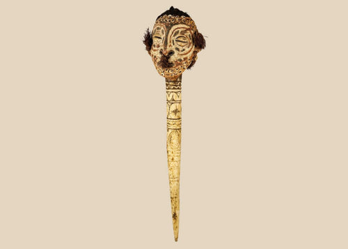 19th-century Sepik River ceremonial bone dagger with carved ancestral head, cowrie shell inlays, human hair adornments, and tribal geometric motifs, used in ritual and initiation rites.