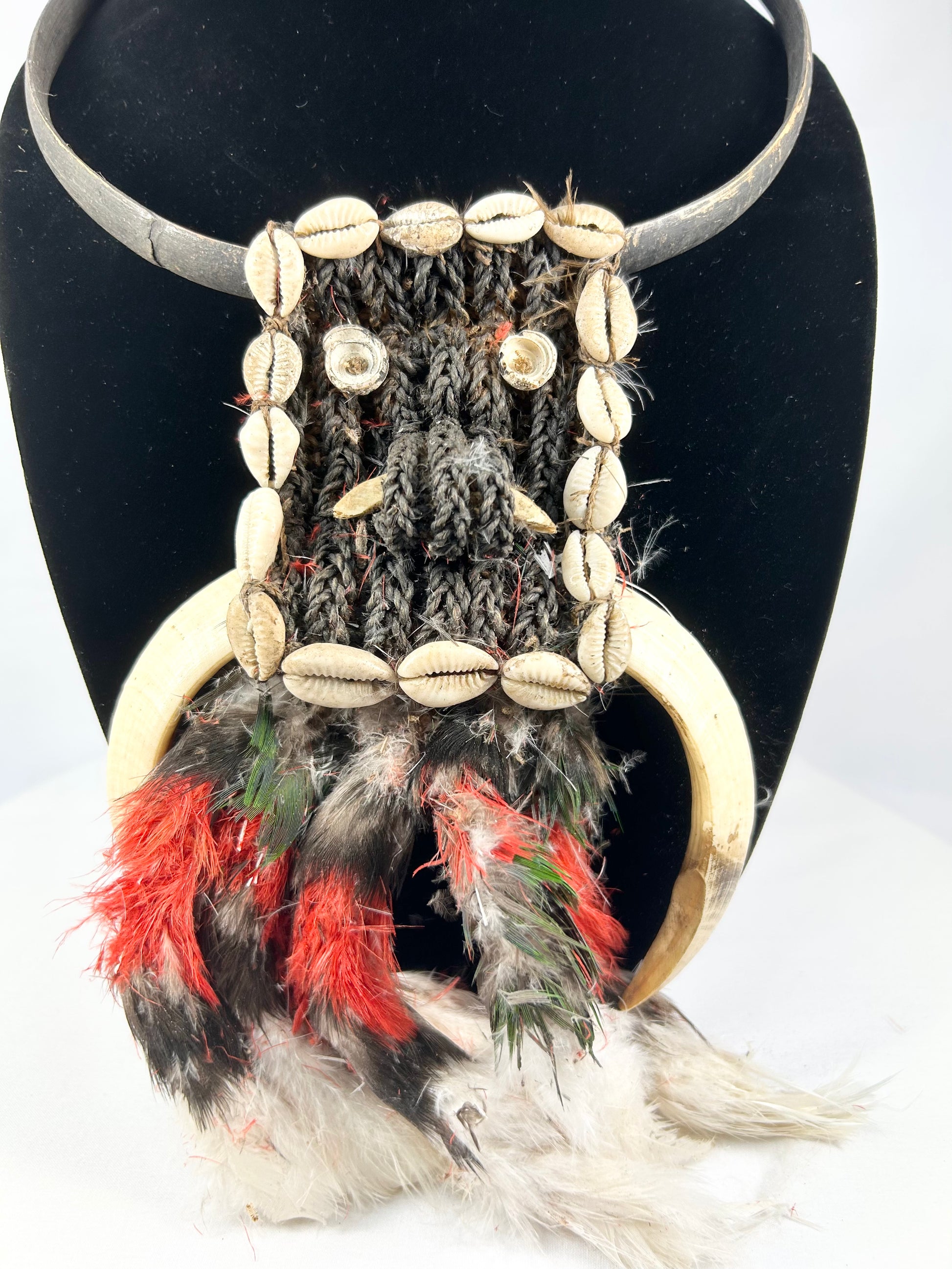 20th century Papua New Guinea tribal ceremonial necklace, braided plant fiber with shell and bone elements, red and black feathers, Oceanic ritual ornament, mounted for display