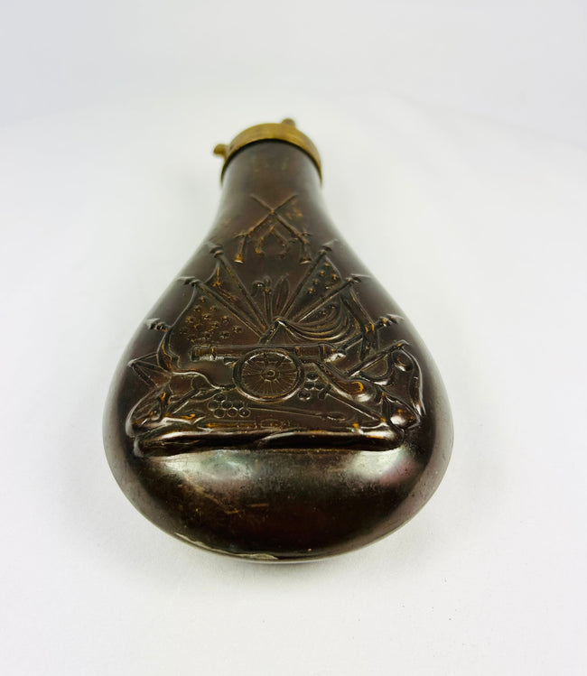 19th century American powder horn style flask in embossed copper with military stand of arms decoration, chocolate brown patina, collectible firearms accessory.
