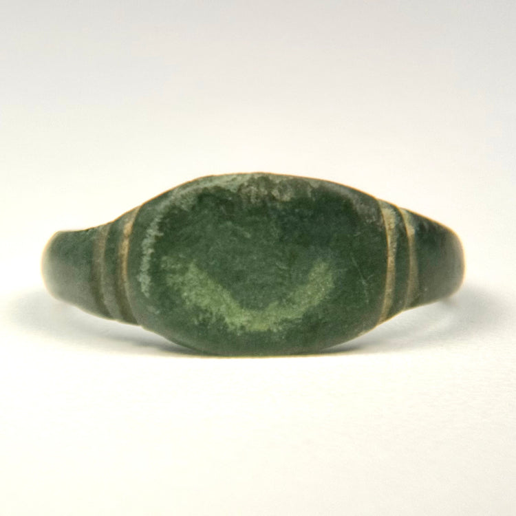Roman Imperial bronze ring showing broad plain bezel and paired incised grooves along the shoulders