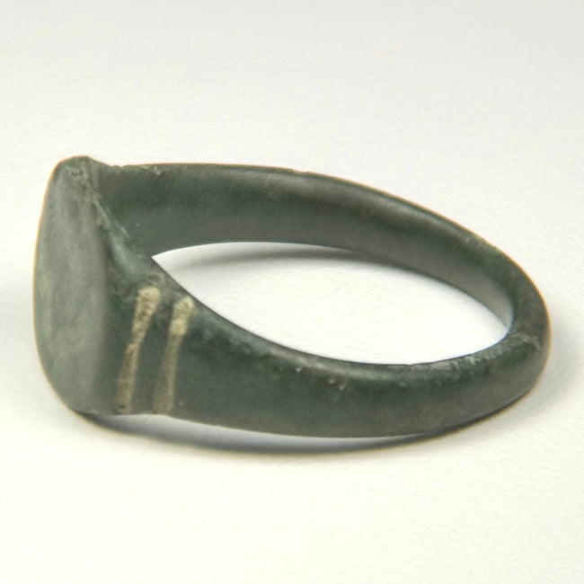 Close-up of Roman bronze ring bezel with olive-green patina, mineral deposits, and age-related surface wear