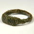 Close-up of ancient bronze ring bezel showing worn geometric engraving and dark green-brown patina