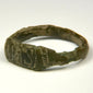 Close-up of ancient bronze ring bezel showing worn geometric engraving and dark green-brown patina