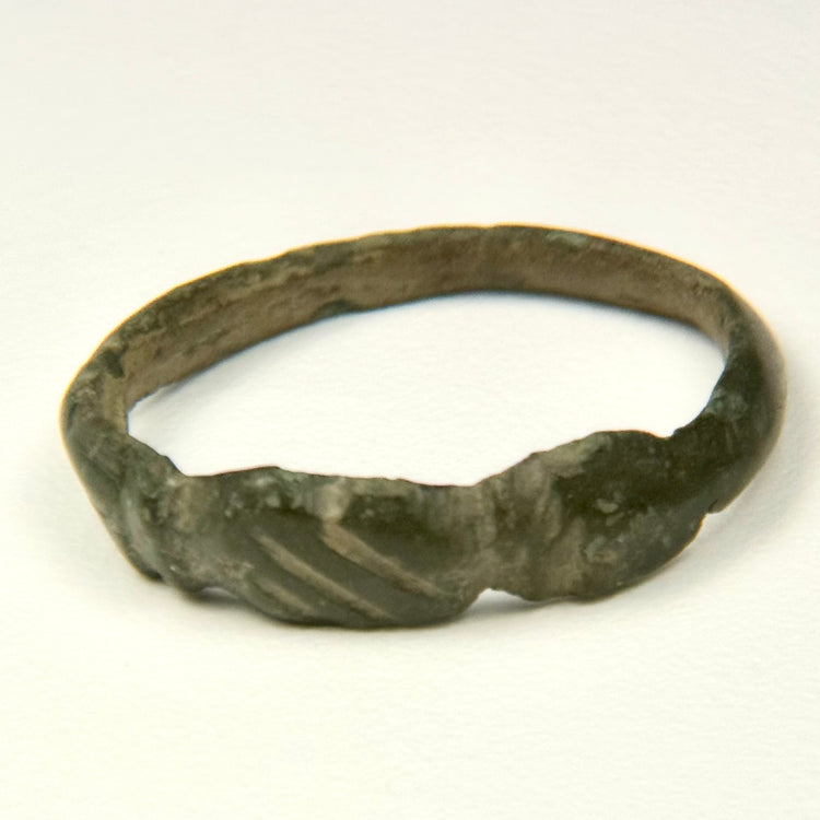 Side view of Late Roman bronze ring showing geometric shoulder grooves and worn archaeological surface