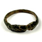 Close-up of ancient bronze ring showing engraved linear bezel, oxidation, and mineralized surface