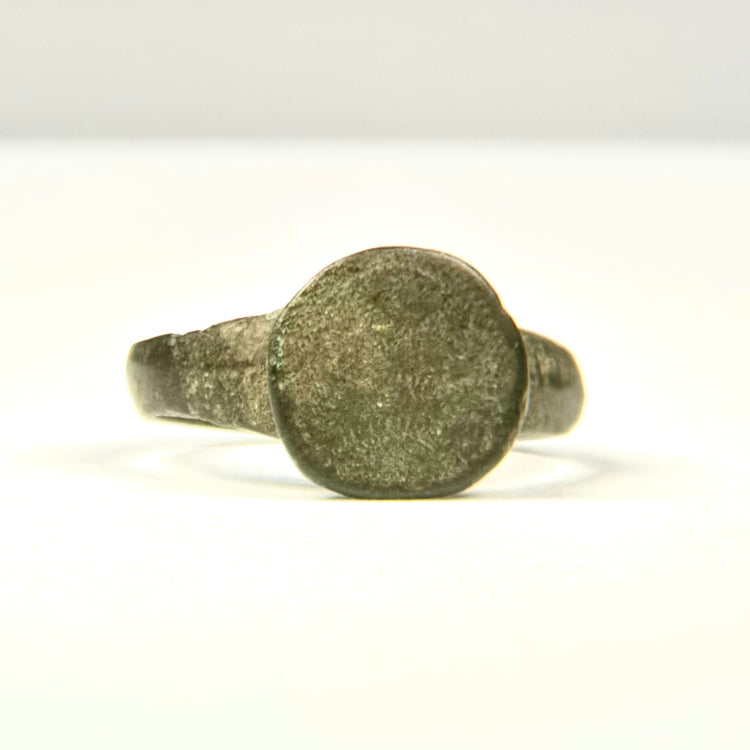 Side profile of ancient bronze finger ring with raised circular bezel and narrowing hoop, Eastern Mediterranean origin