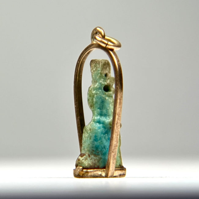 Late Period to Ptolemaic Egyptian amulet showing a standing protective or funerary figure with worn blue-green glaze and gold setting.