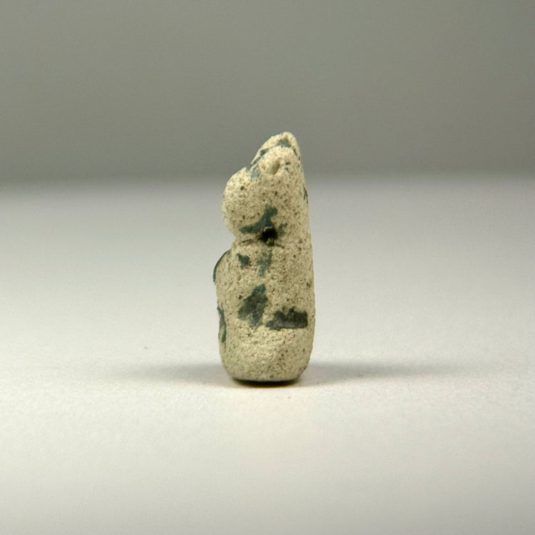 Late Period to Ptolemaic Egyptian faience cat amulet with upright ears, seated posture, and naturally weathered surface.