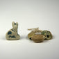 Ancient Egyptian faience Bastet cat amulet displayed with three scarab charms, dating from the Late Period to Ptolemaic Period.