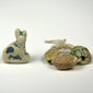 Collection of Ancient Egyptian amulets featuring a seated faience cat and three carved scarabs with surviving glaze and incised decoration.