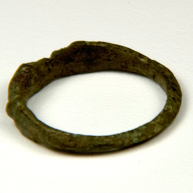 Side view of ancient Roman bronze finger ring with broad shoulders and aged green-brown patina