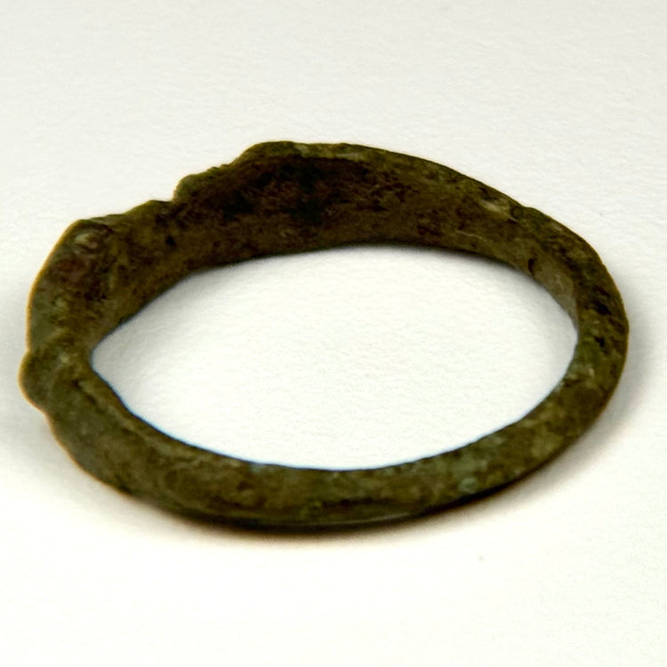 Side view of ancient Roman bronze finger ring with broad shoulders and aged green-brown patina