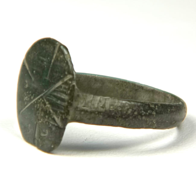 Close-up of Byzantine bronze signet ring with weathered incised cruciform bezel and naturally aged surface