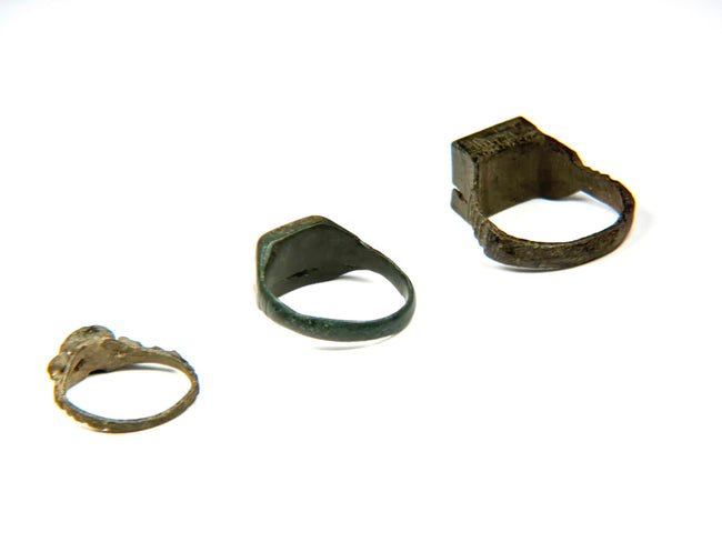 Three Late Roman to Early Byzantine bronze finger rings shown from rear and side angles, including square signet and oval bezel forms, circa 3rd–7th century CE