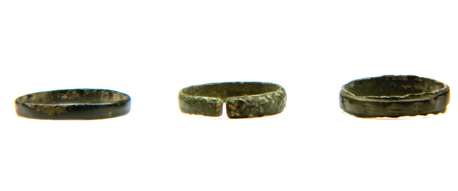 Back view of three Late Roman to Early Byzantine bronze finger rings, showing plain and open-ended bands with aged green-brown patina, circa 3rd–7th century CE.