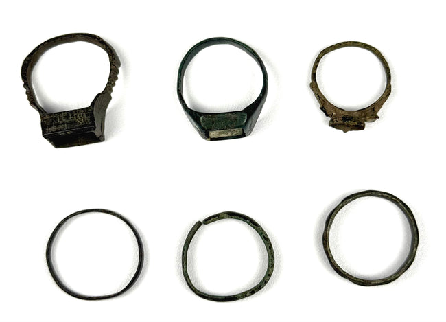 Top and front views of six ancient bronze finger rings with decorative bezels and simple bands, circa 3rd–7th century CE