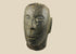 Antique Polynesian volcanic stone head sculpture, carved with stylized facial features and linear hair details, used for ancestor veneration, photographed on a white background.