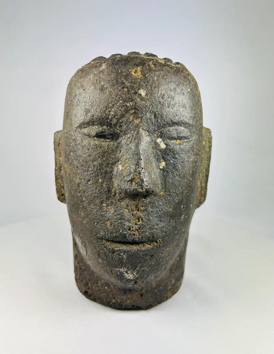 Antique Polynesian volcanic stone head sculpture, carved with stylized facial features and linear hair details, used for ancestor veneration, photographed on a white background.