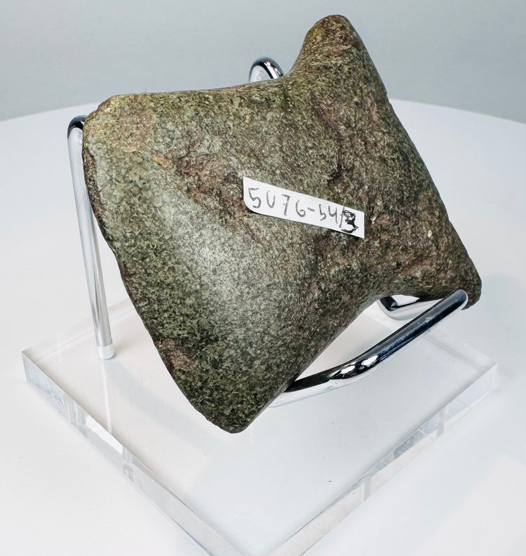 Angled view of an ancient Andean notched axe showing its rounded cutting edge, surface patina, and evidence of repeated sharpening.