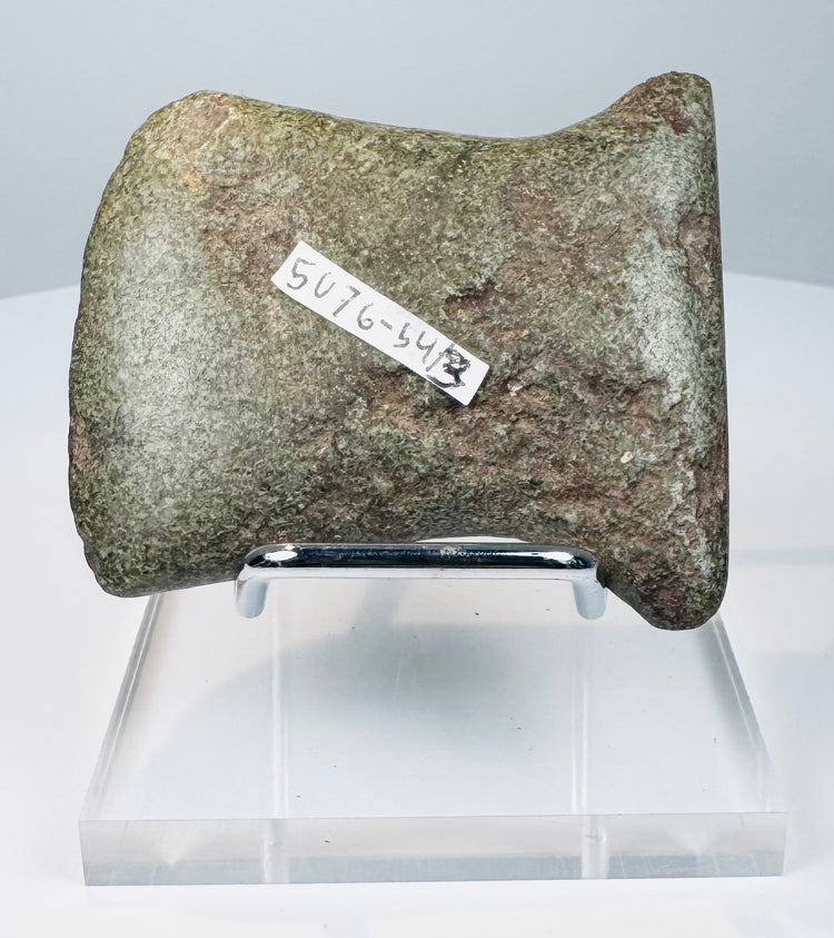 Ancient Pre-Columbian ground stone axe from the Andean region showing side notches for hafting and a worn beveled cutting edge.