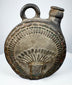 Dark-fired ceramic canteen with raised human face and feather-like ornament
