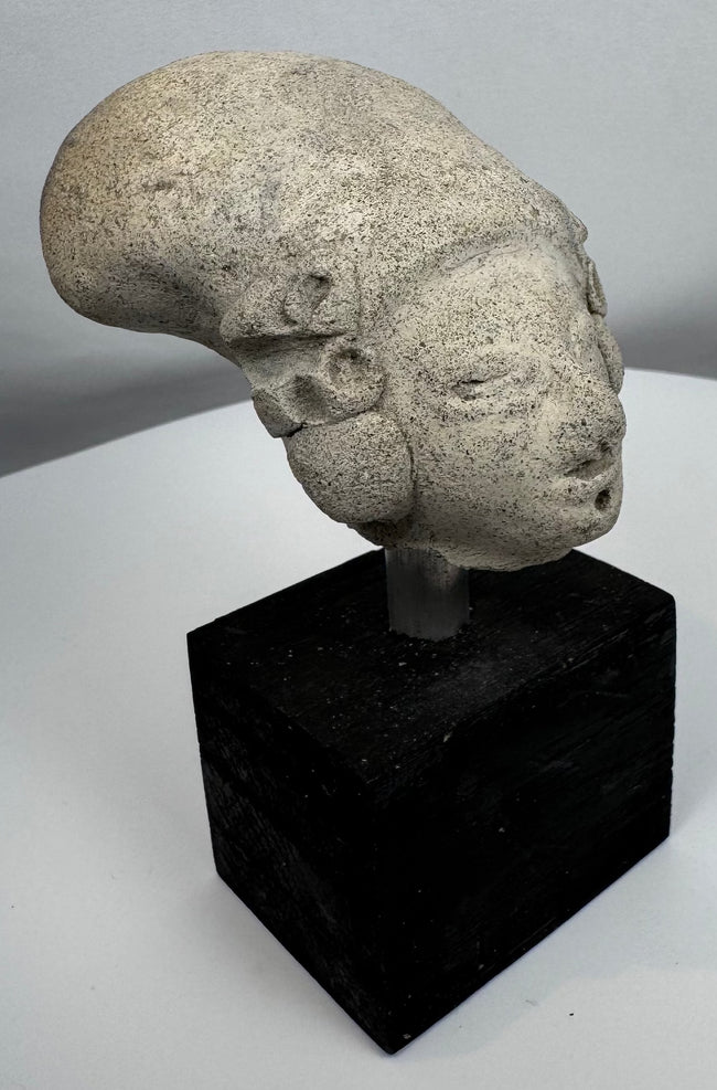Ancient West Mexican terracotta head fragment featuring large ear spools and closed eyes.