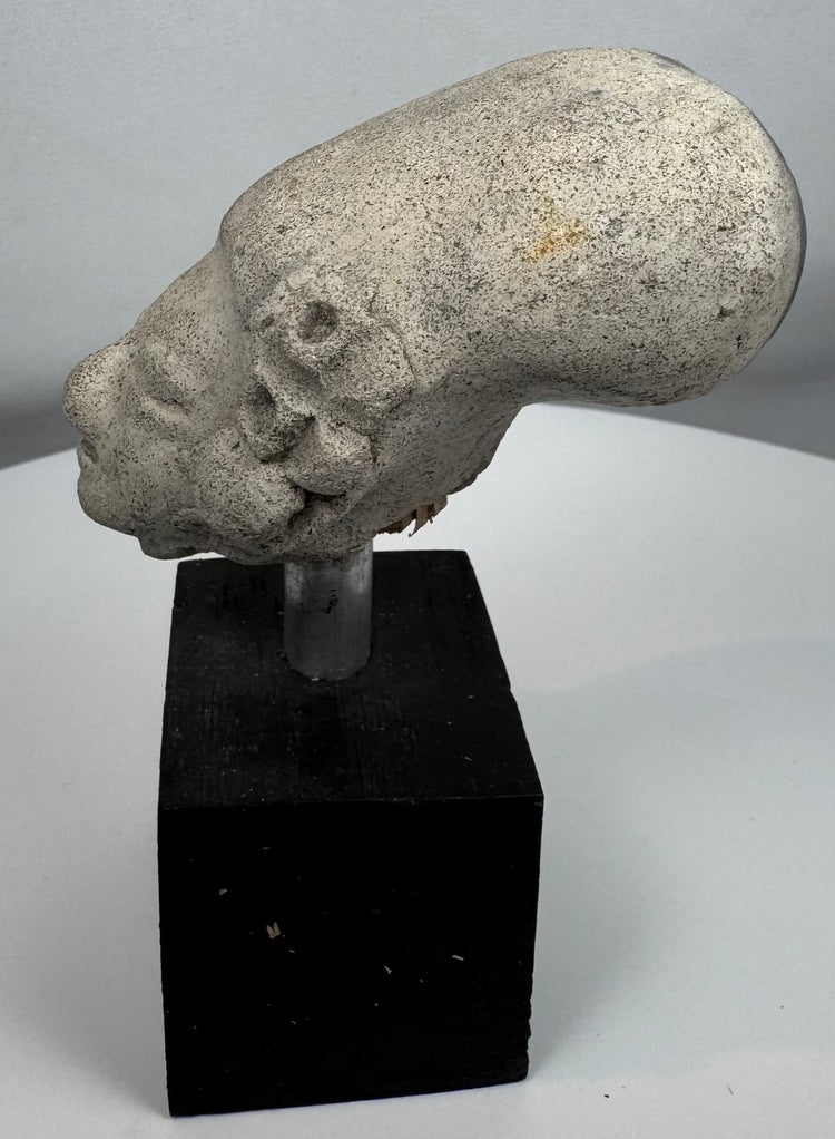 Ancient Mesoamerican effigy head displaying prominent ear ornaments and stylized facial features.