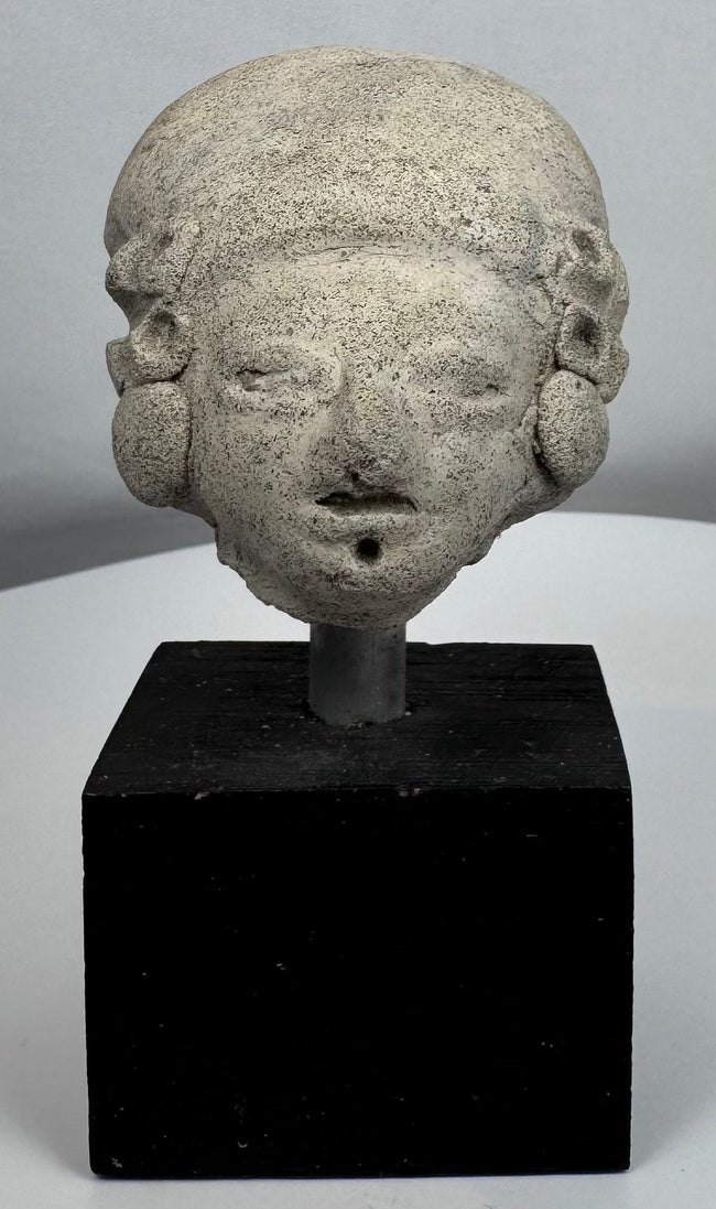 Ancient terracotta head with cranial modification and large circular ear spools from Pre-Columbian Mexico.