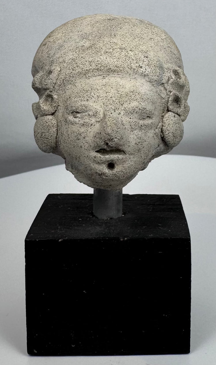 Ancient terracotta head with cranial modification and large circular ear spools from Pre-Columbian Mexico.